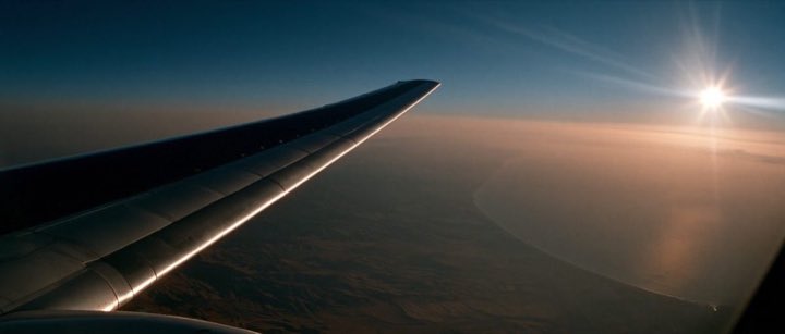 Vliegticket naar Israël — vliegtuigvleugel boven de kust bij zonsondergang